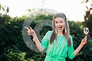 Emotionaly brunette girl in green dress surprised screaming and pointing at side.