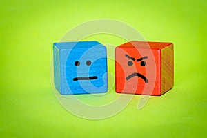Emotions, Blue and Red Wooden Block, Hand Painted Facial Expression, Sadness and Rage, Dissatisfaction, Green Background