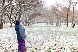 Emotions in the child`s view, confusion and sadness in the eyes of the child. Late autumn and the first snow in the park