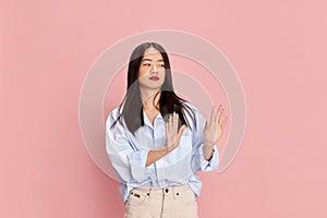 Emotions of disapproval. Portrait of young beautiful girl in casual clothes posing against pink studio background