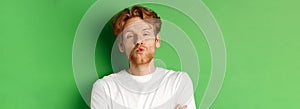 Emotions and fashion concept. Silly redhead guy with beard pucker lips and leaning for kiss, standing over green