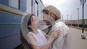 Emotions joy of happy young woman embrace man and laughs near railway carriage on Train Station after separation