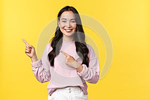 Emotions, lifestyle and fashion concept. Smiling attractive asian woman in stylish casual clothes pointing fingers upper