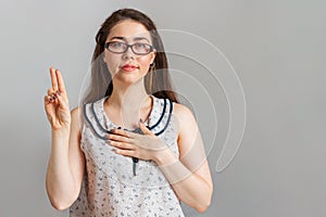 Emotions and people. A young woman in a blouse and glasses swears allegiance. Copy space