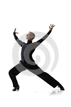 Portrait of young graceful male dancer, flexible man in black stage costume dancing ballroom dance isolated on white