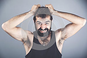 Emotions, stress, madness and people concept - crazy shouting man rending ones hair in t-shirt over gray background