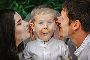 Emotions and surprised face of the child. Dad and mom whispering in the ear of his little son