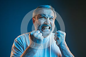 The senior emotional angry man screaming on blue studio background photo