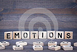 Emotions word written on wood block. Dark wood background with texture