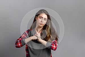 Emotions. A young woman with a discontented face rubs her fists together. Copy space