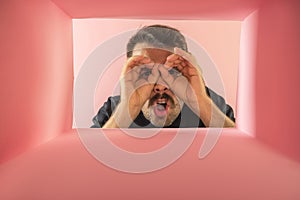 Emotive man looking inside carton box with shock.