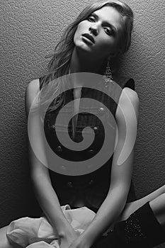Emotive portrait of a beautiful fashion model posing over gray background. Black and white monochrome studio photo