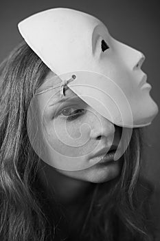 Emotive portrait of a beautiful model with a white mask volto bianco on her head. Daylight. Close up. Black and white photo