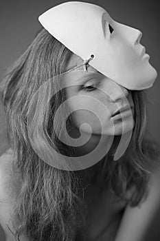 Emotive portrait of a beautiful model with a white mask volto bianco on her head. Daylight. Close up. Black and white photo