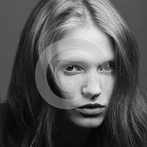 Emotive portrait of a young beautiful girl with curly long hair posing over black background. Perfect skin and hair. Spa salon.