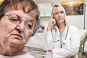 Empathetic Doctor Standing Behind Troubled Senior Adult Woman In Office