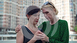 Empathetic woman calming down stressed anxious desperate friend outdoors on city street. Portrait of caring Caucasian