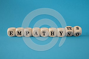 Empathy yes or no symbol. Turned wooden cubes and changes words empathy no to empathy yes on a beautiful blue background.