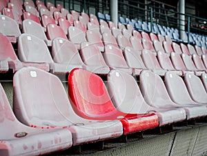 Emphasis on one unlike chair among the rows of seats in the stands of the stadium