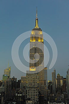 Empire State Building and skyline at dusk with lights on