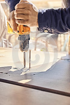 Employee assembles dining table with electric screwdriver outdoors