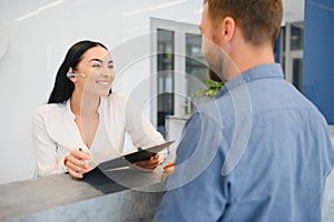 The employee of the beauty salon meets the client in the reception of a modern beauty salon. A man signs a paper with