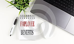 EMPLOYEE BENEFITS text on notebook with laptop, mouse and pen