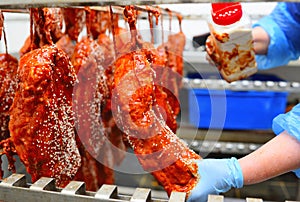 an employee of a butcher& x27;s shop or meat-packing plant sprinkles appetizing pieces of pork in tomato sauce with