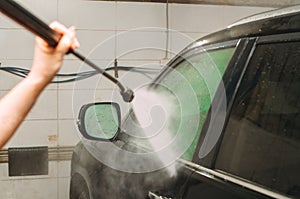 An employee of the car wash thoroughly washes conducts detaling and applies protective equipment to the body of an expensive car
