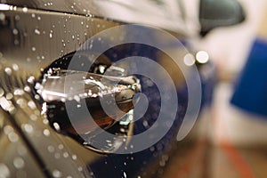 An employee of the car wash thoroughly washes conducts detaling and applies protective equipment to the body of an expensive car