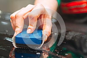 An employee of the car wash thoroughly washes conducts detaling and applies protective equipment to the body of an expensive car