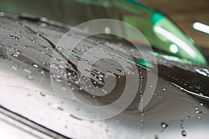 An employee of the car wash thoroughly washes conducts detaling and applies protective equipment to the body of an expensive car