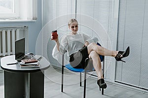 Employee care. Relaxed happy young business woman entrepreneur put legs on table, talking on cell phone, drinking coffee