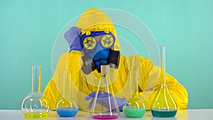 Employee of a chemical laboratory in a protective yellow suit, gloves, a mask with the sign biological hazard rearranges