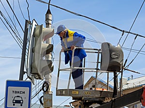 The employee of city services serves a traffic light on Lenin`s area