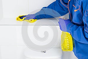 An employee of the cleaning company wipes the tiles in the bathroom using special products photo