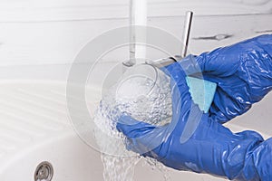 An employee of the cleaning service of residential premises washes a glass Cup with a sponge