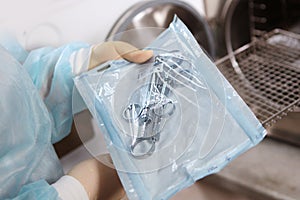 An employee of the clinic puts dental instruments in individual packaging in a dry-firing cabinet for subsequent sterilization.