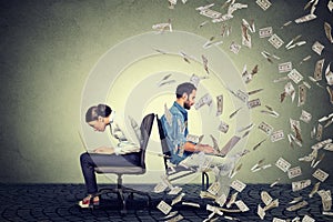 Employee compensation economy concept. Woman working on laptop sitting next to man under money rain.