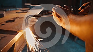 An employee cuts a piece of metal with a torch.