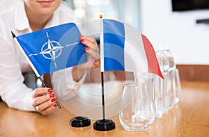 Employee of delegation prepares negotiating table - sets up flag of NATO & x28;OTAN& x29; and France