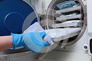 An employee of the dental clinic takes out sterilized tools from the dry-burning Cabinet. The concept of sterility and hygiene in