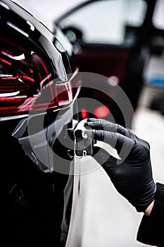 employee of a detailing studio or a car wash applies a ceramic or graphene coating