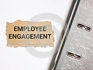 Employee engagement written on brown paper strip with ring file on the desk.