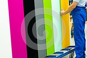 An employee in a glass factory submits painted panes, Various colors