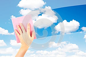 Employee hand cleaning a glass with rain drops and blue sky background