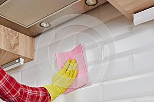 Employee hand in rubber protective glove with micro fiber cloth washing a ceramic tiles in the kitchen