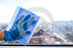 Employee hand in rubber protective glove with micro fiber cloth wiping window from dust. copy space, General cleaning