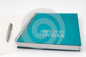 Employee Handbook or manual with a pen and paper on a white table in an office.