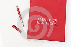 Employee Handbook or manual with a pen and paper on a white table in an office.